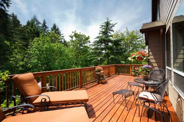 A hardwood deck with chairs and flowers.