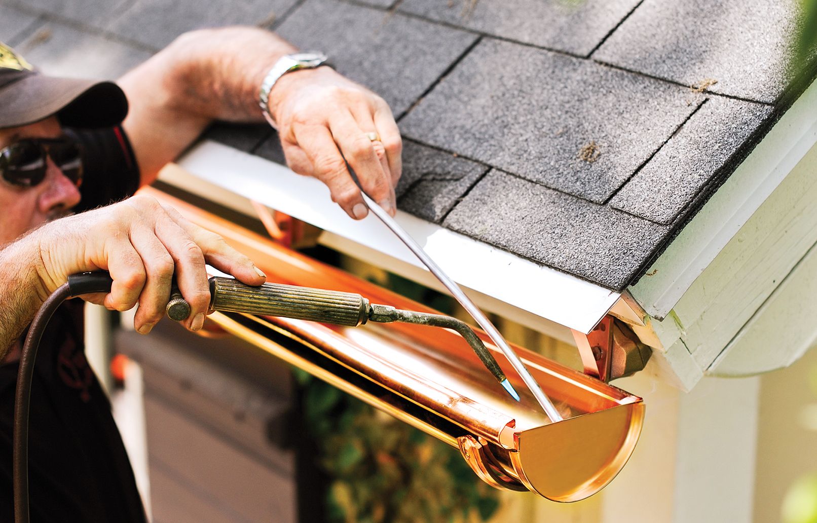 A man solders the seams and end caps of his half-round gutter system.