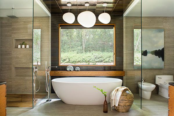 A bathtub in front of a tile wall with a window, white light fixtures hang from the ceiling.