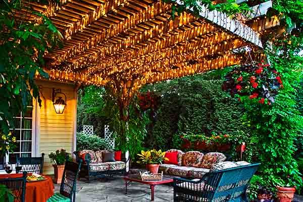 A pergola covered in string lights lights up an outdoor patio.