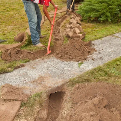A person digs a path to lay inlet pipe for the rain garden.