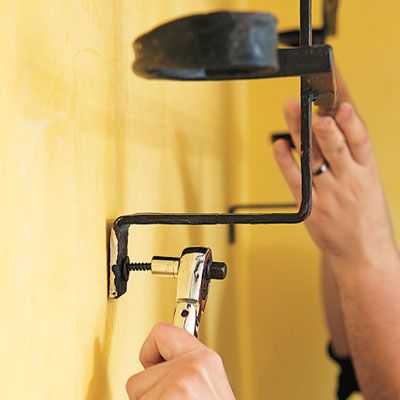 A person holding up a pot rack while steadying it with fasteners.