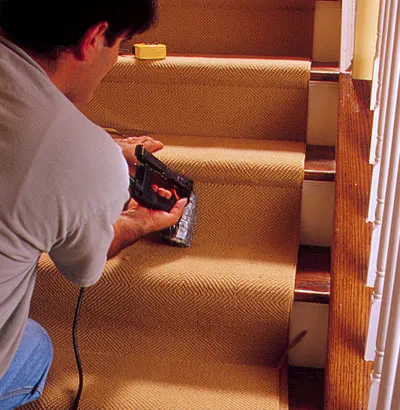 A man install carpet on the stairs.