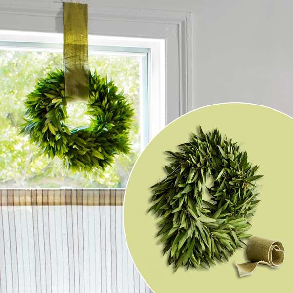 An herb wreath hanging in the window of a dining room.