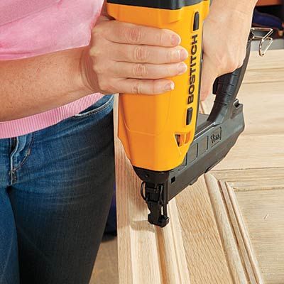 A person secures the molding to the door with a nailer to turn it into a headboard.