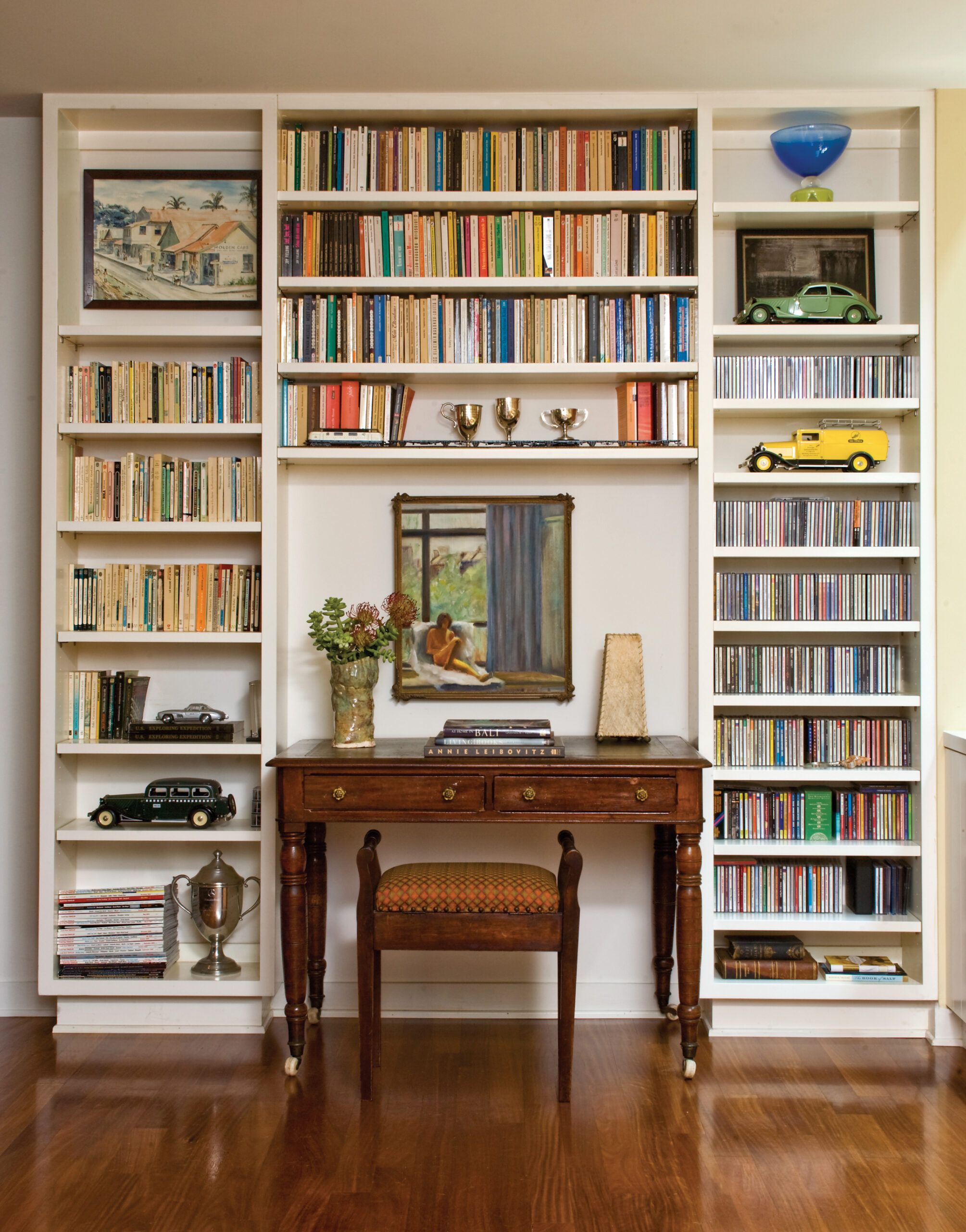 A shelving unit with books, trophies, and knick knacks.