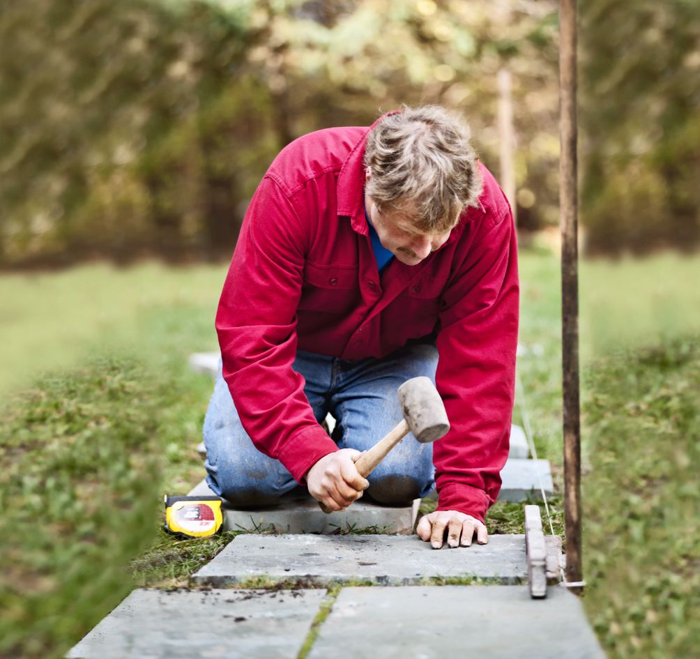 A man hammering stone into the ground to create a pathway.