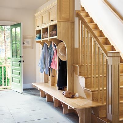 a mudroom design along the sides of a stairwell with room to hang clothes and store items