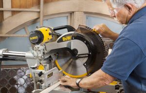 A man using a table saw to cut components for a spindle headboard.