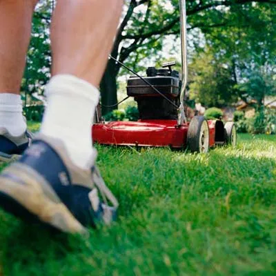 A red lawn mover cuts the sod grass.