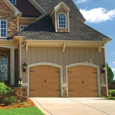 House with two matching single car garage doors that are both wooden and have black hardware.