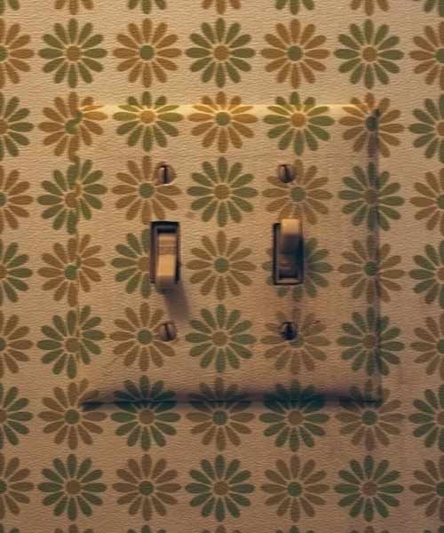 A light switch decorated with wall paper scraps.