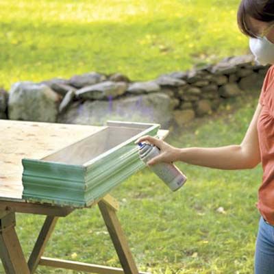 A woman seals the finish of a window box.