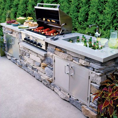 Outdoor kitchen with a large grill, sink, and fridge. 