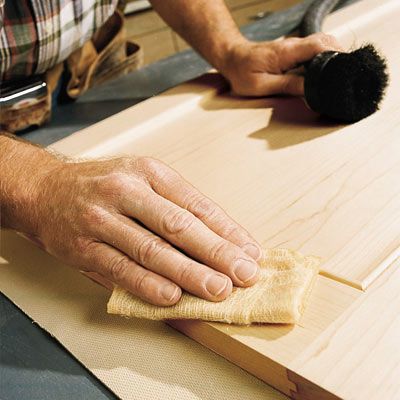 A person removes any remaining dust after using a random orbit sander.