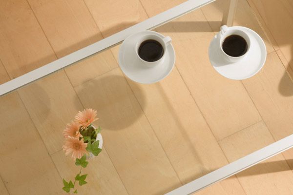 A glass table with a pair of coffee cups on top of it.