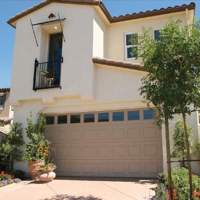 Tan composite garage door on a Spanish style house.