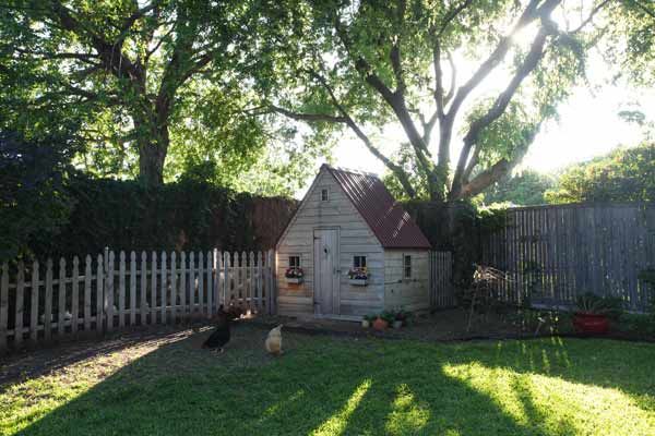 An outdoor chicken coop beside a garden.