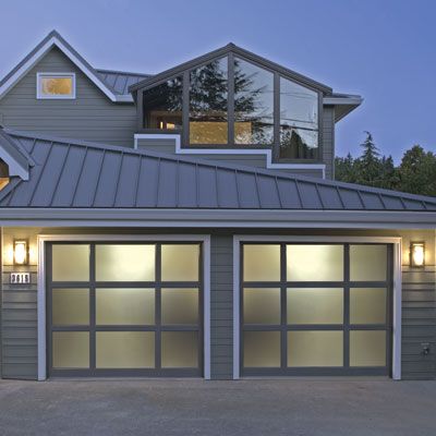 Modern frosted glass garage doors on a house with gray siding.