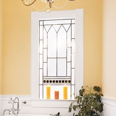 An ornate privacy window above a bathtub.