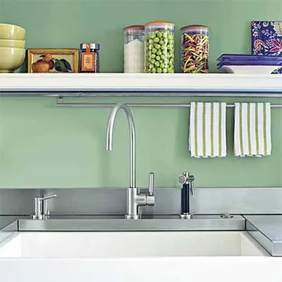 A green painted wall with a sink and shelf in front of it.