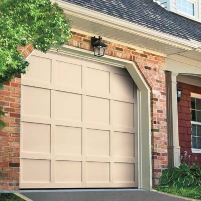 A tan neo-colonial garage door on a brick house.