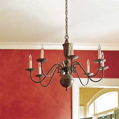 A chandelier hanging in front of a red painted wall.