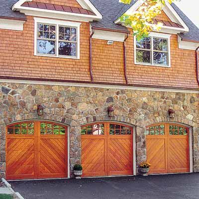 Three wooden traditional garage doors with windows at the top of each.