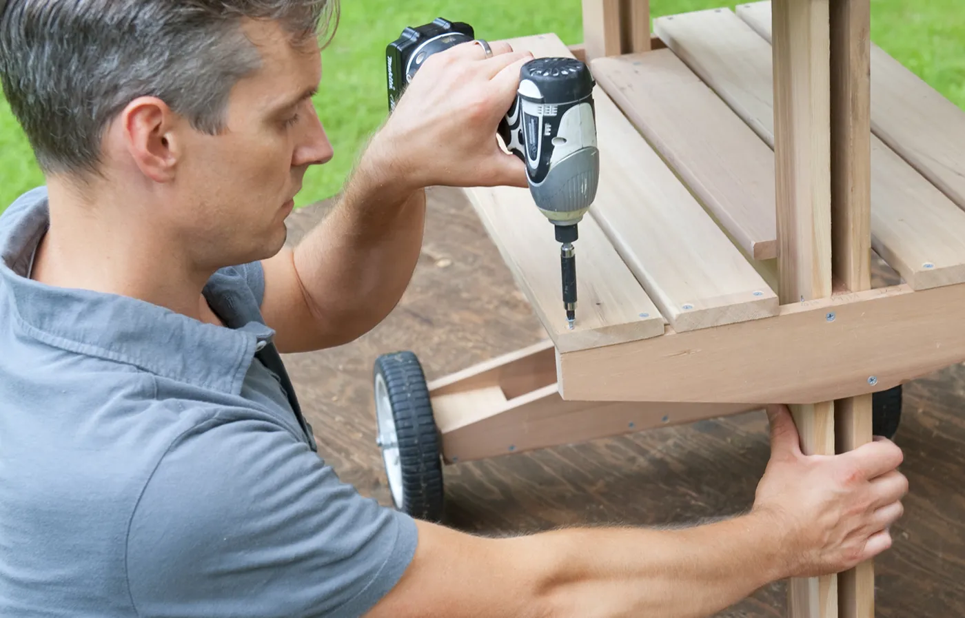 A person securing the shelf slats on the rolling grill table.