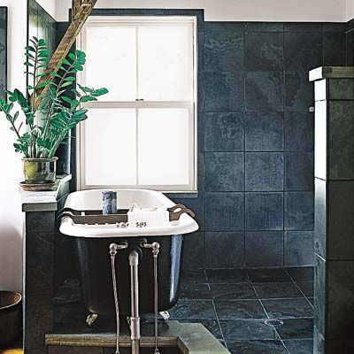 A bathroom covered in large dark ceramic tiles.