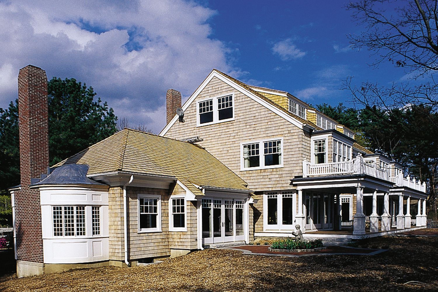 A white home with a chimney and a lawn.