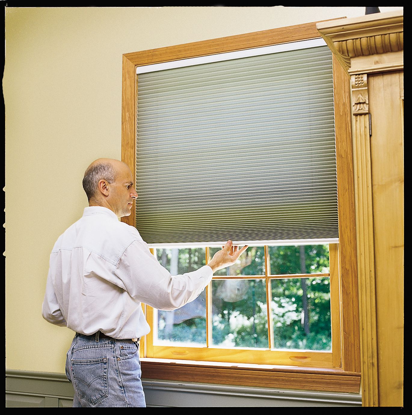 A man pulls down cellular window treatments.