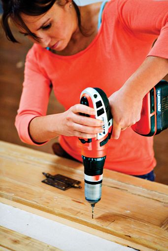 Woman predrilling screw holes in shutters