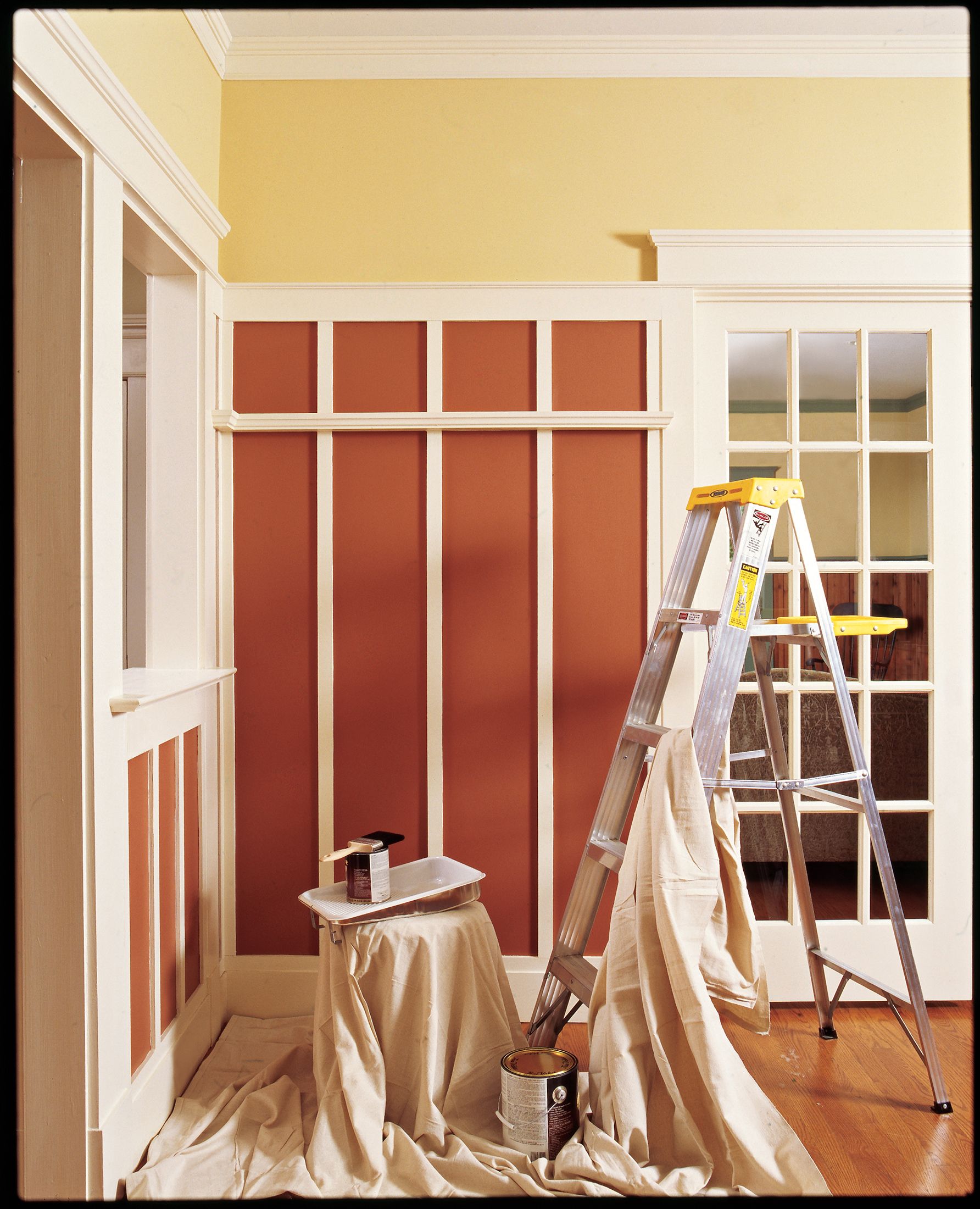 A ladder and paint cans in a newly painted room.