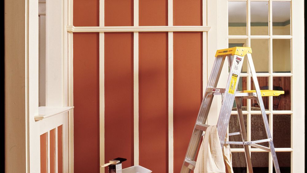 A ladder and covered objects in a room being prepared for painting.