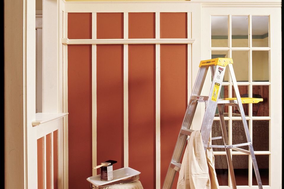 A ladder and covered objects in a room being prepared for painting.