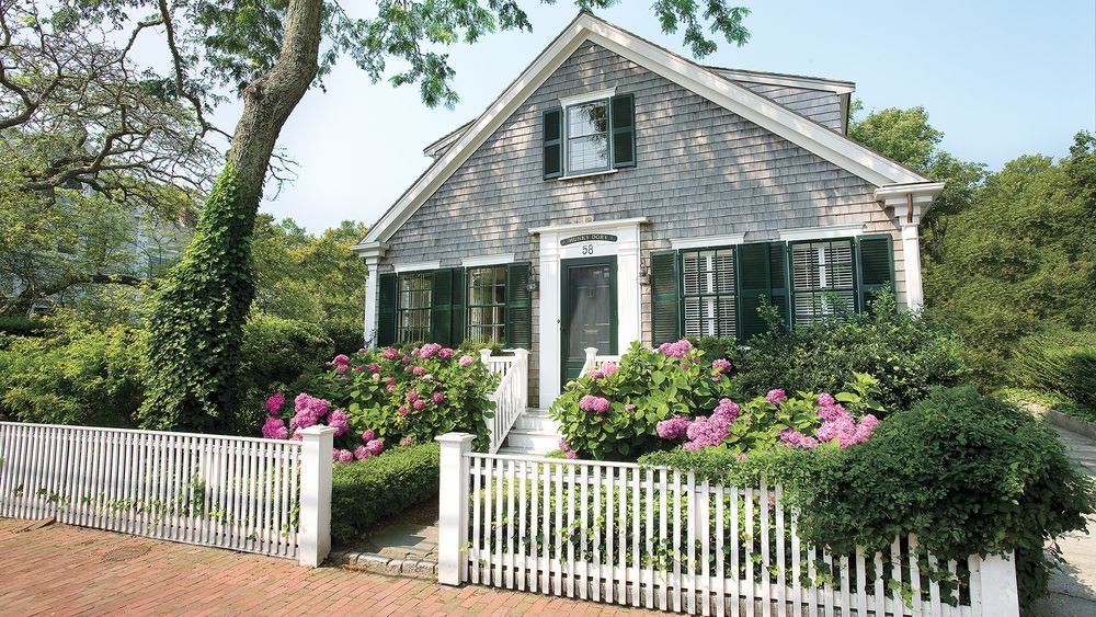 A home with a white wooden fence surrounding it.