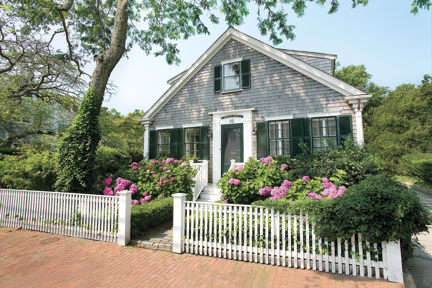 A home with a white wooden fence surrounding it.