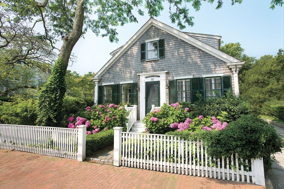 A home with a white wooden fence surrounding it.