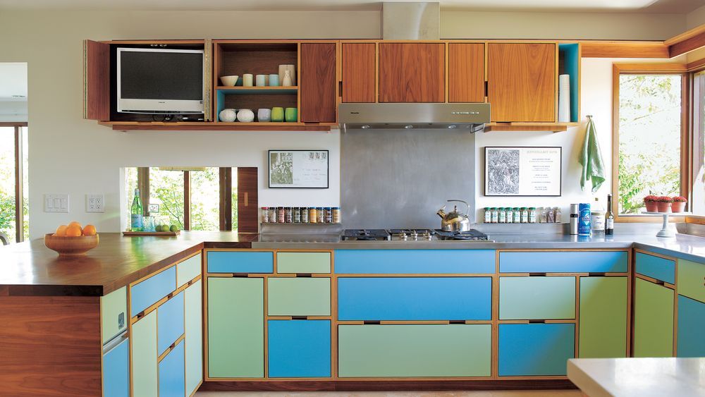 A modern kitchen features colorful laminate cabinets in blue and green, with wood accents.