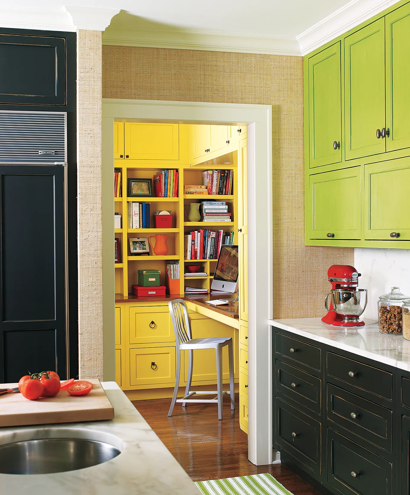 Bright yellow study room adjacent to a kitchen with green cabinets.