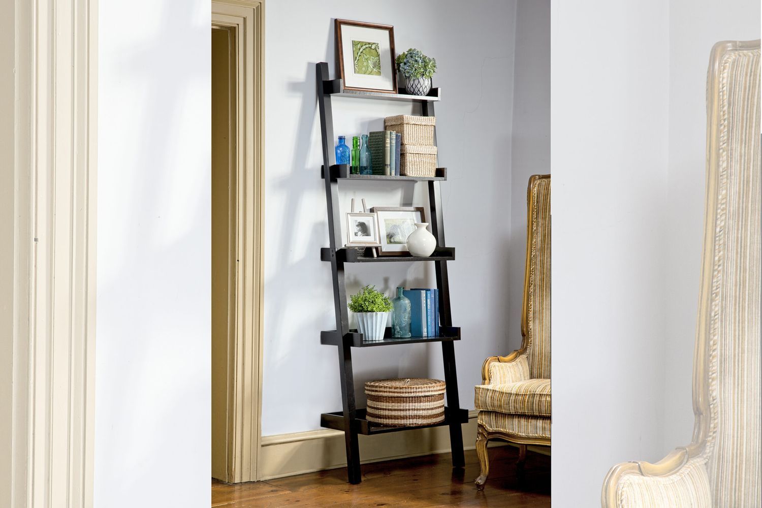 An image of a ladder bookshelf with several items including books and a framed photo on it.