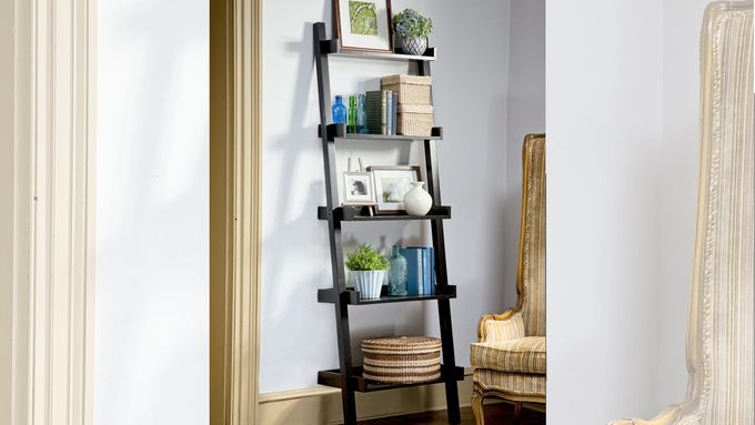 An image of a ladder bookshelf with several items including books and a framed photo on it.