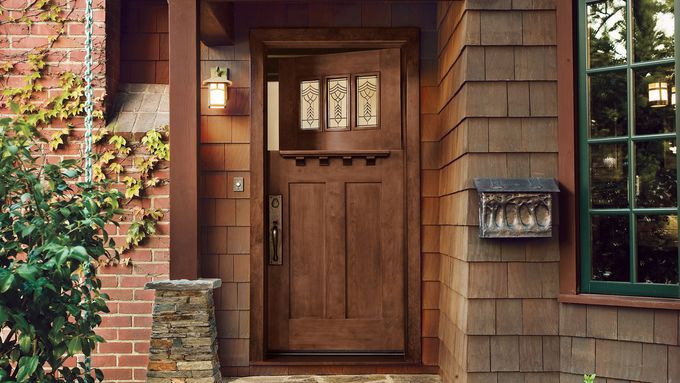 A fiberglass entry door with three small intricate glass windows and a shelf.