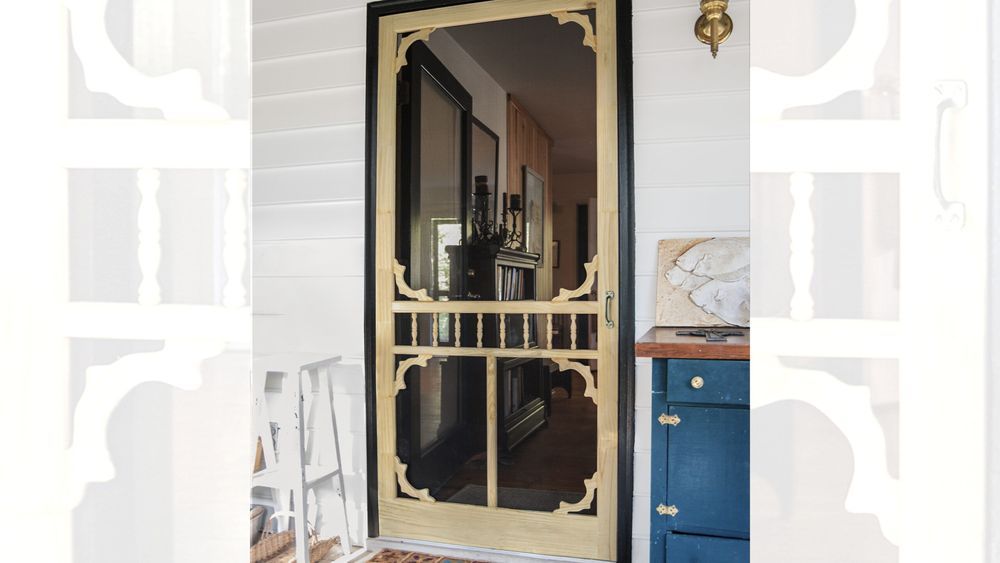 A vintage screen door in front of a brown doormat.