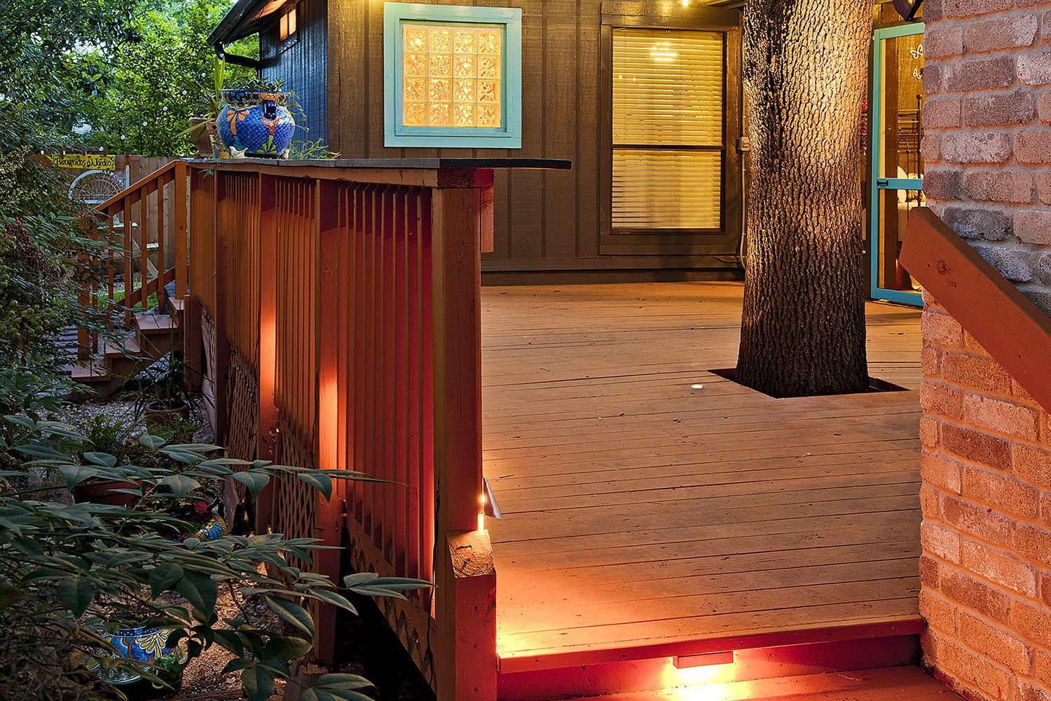 A deck with yellow lights hanging over the rop of it.