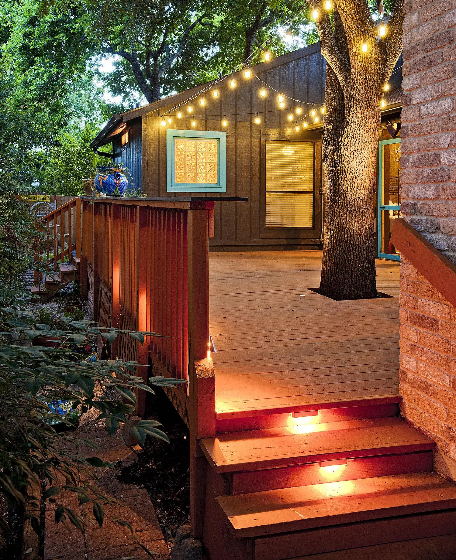 A deck with yellow lights hanging over the rop of it.