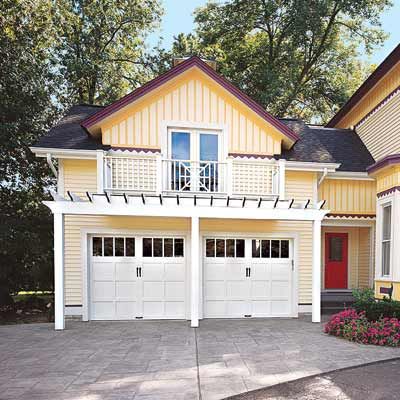 Two white garage doors with a pergola overtop.