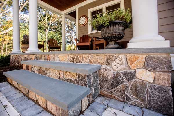 Stone veneers on a the front of steps leading up to a front porch.