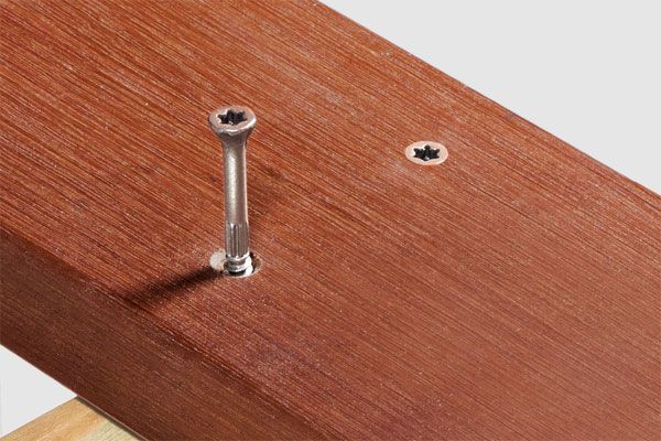 a hardwood board being fixed to a joist with a screw.